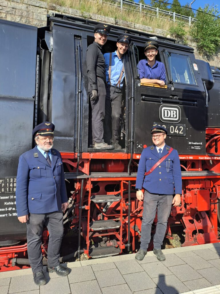 Mitarbeiter und Ehrenamtliche der 3Seenbahn vor historischer Dampflok im Schwarzwald – engagiertes Team der Drei-Seen-Bahn bei einer Museumszugfahrt.
