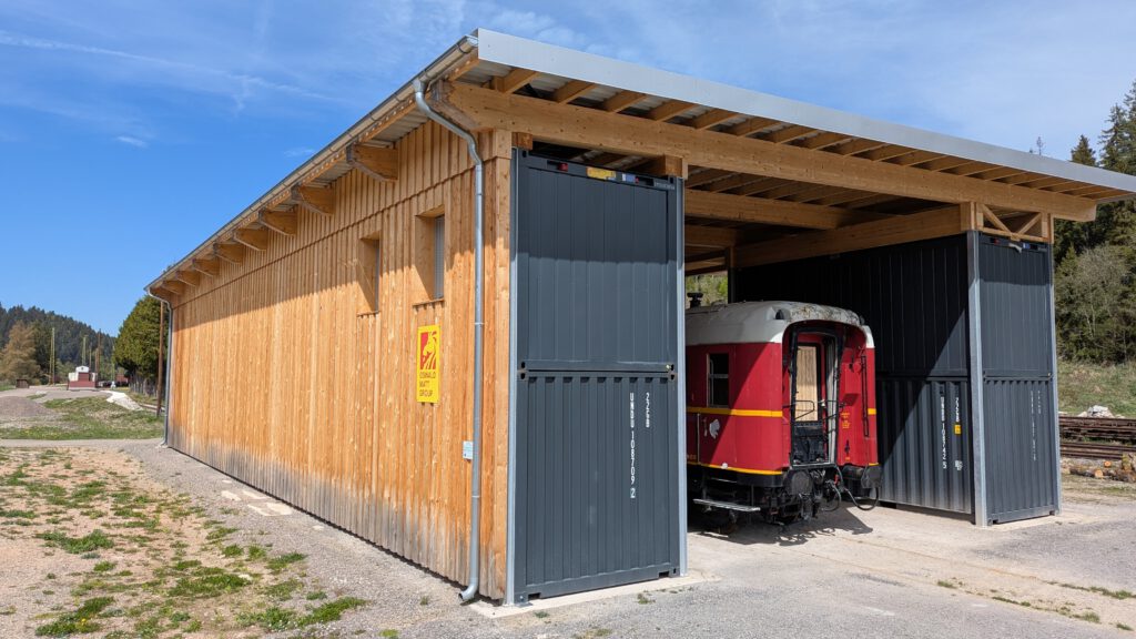 Die fertige Container-Werkstatt der 3Seenbahn im Schwarzwald mit historischem Bahnwagen – moderner Unterstand für die Restaurierung und den Erhalt der Museumsbahn der Drei-Seen-Bahn.