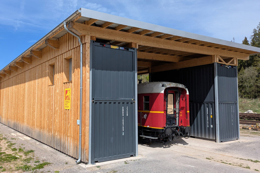 Die fertige Container-Werkstatt der 3Seenbahn im Schwarzwald mit historischem Bahnwagen – moderner Unterstand für die Restaurierung und den Erhalt der Museumsbahn der Drei-Seen-Bahn.